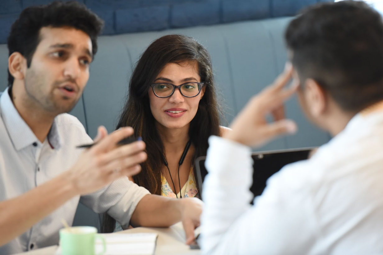 Two men and a woman are sitting around a table discussing something