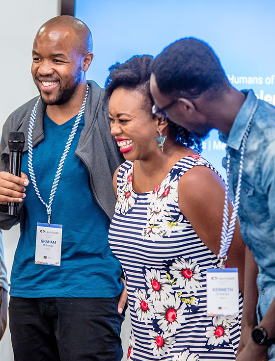 Three individuals are hosting an event, with one of them holding a microphone.