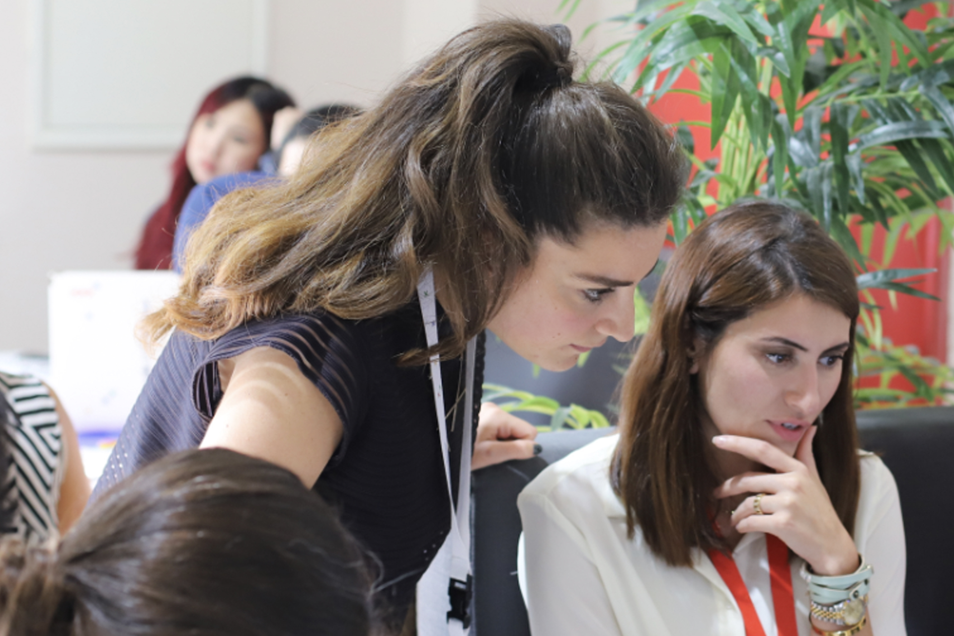 Two ladies are discussing and looking at screen.