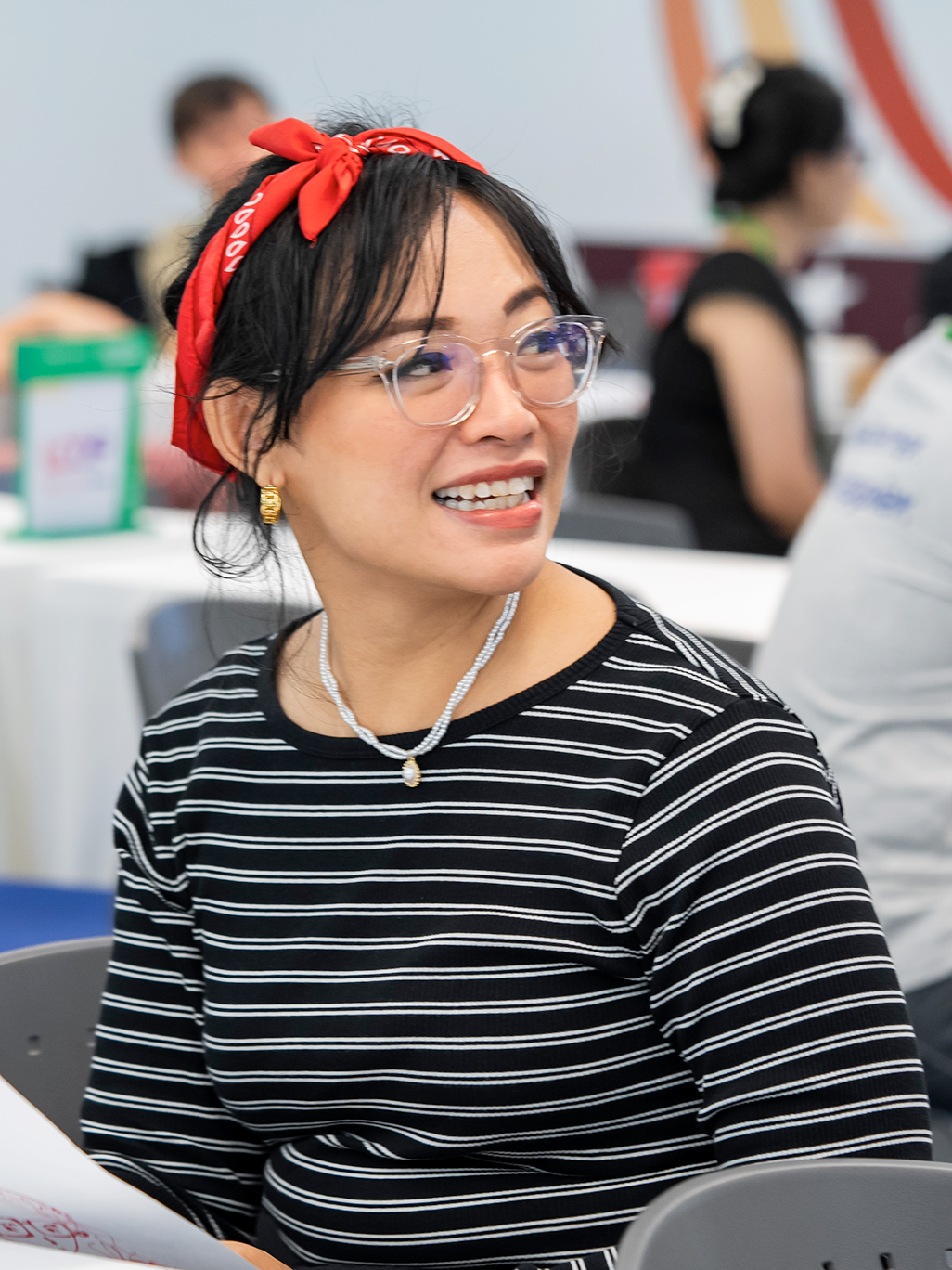 A woman in a black t-shirt looking across and smiling.