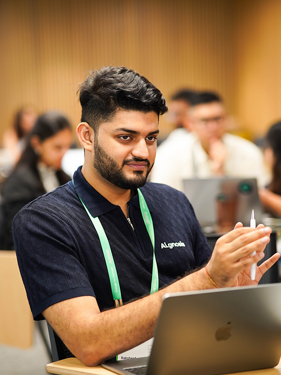 Person wearing an ID card speaking near an open laptop.
