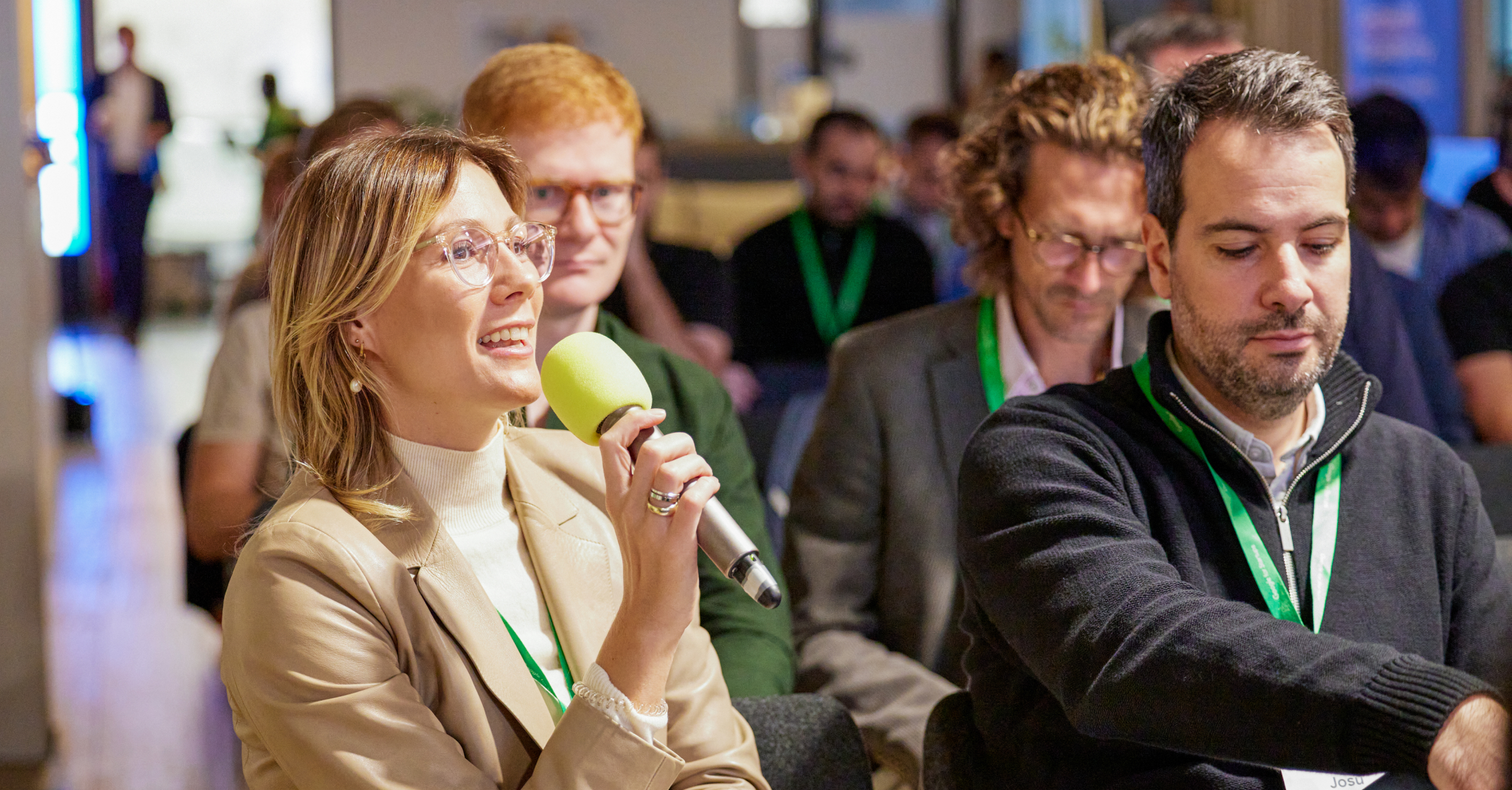 A woman sits with some people and holds the mic in hand.