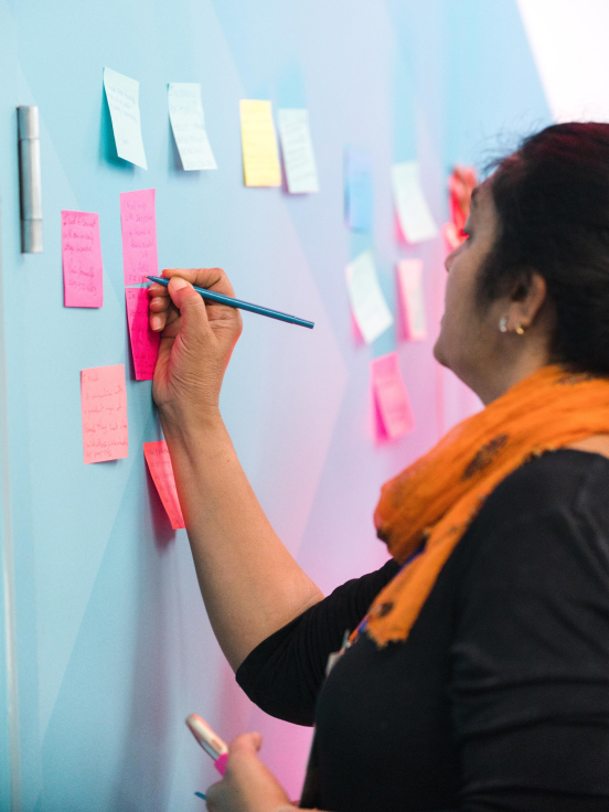 A woman writing something on sticky note on board