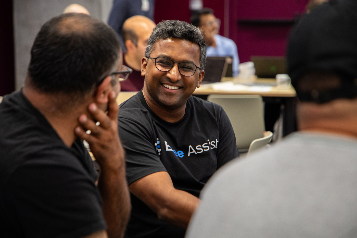 A bespectacled man engages in conversation with a smiling individual.