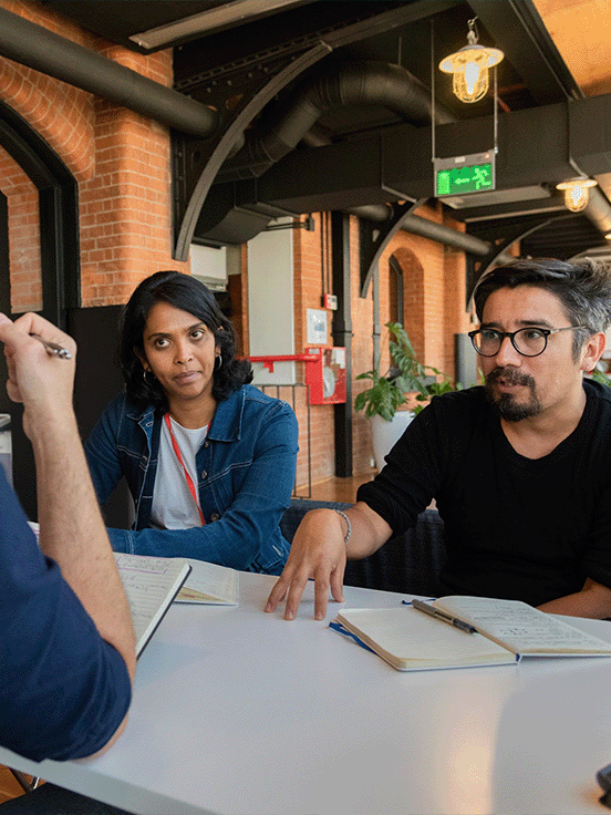 A seated group is discussing a topic with notepads in front of them.