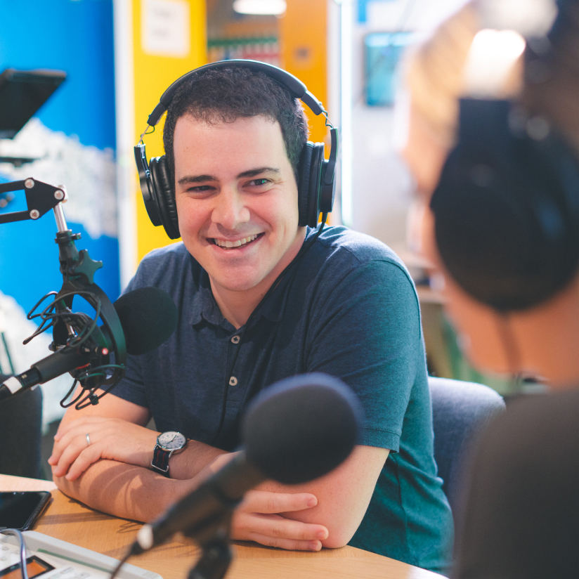 A man sitting in front of a microphone in a recording studio