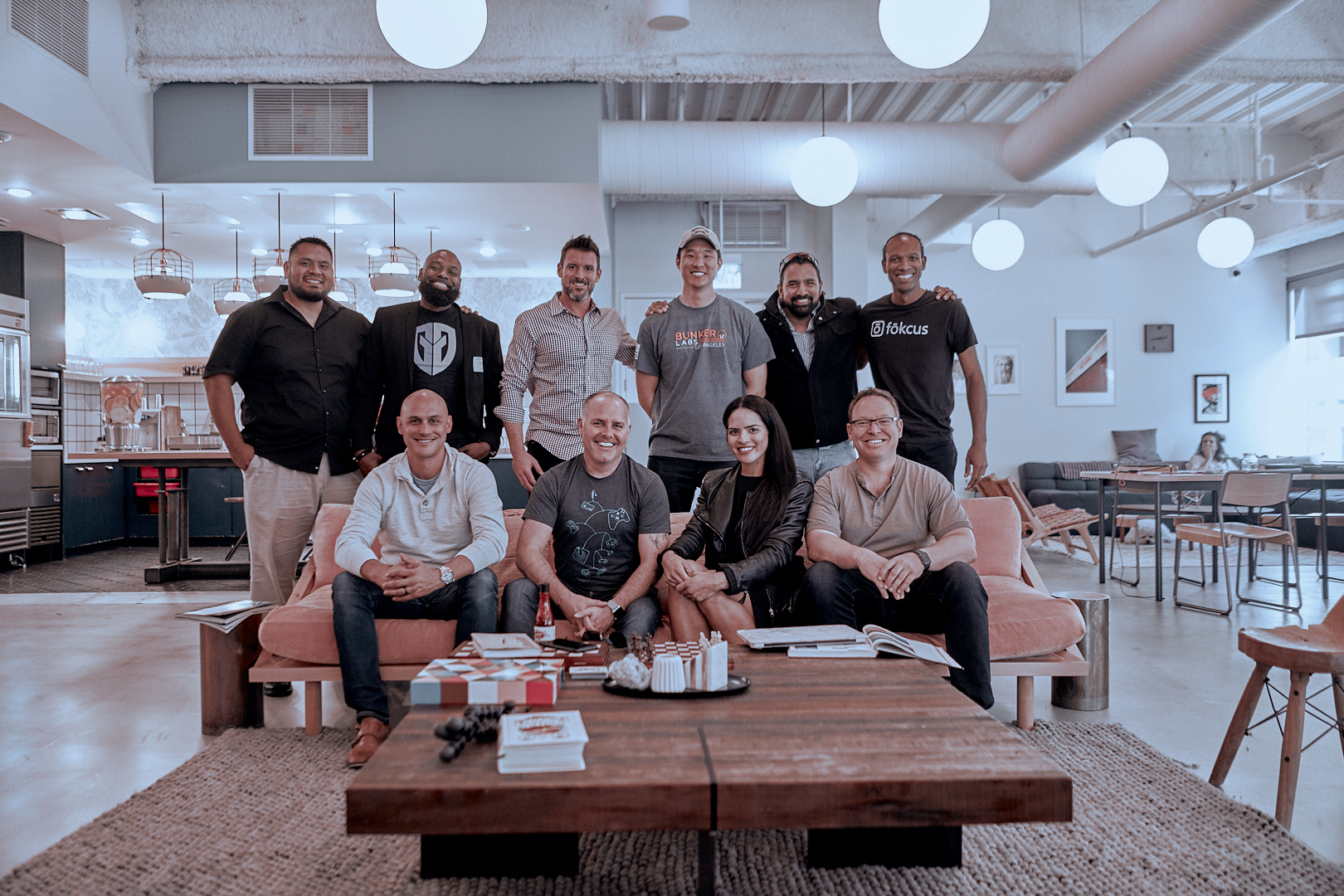 Six people stand and four people sit on a couch smiling at the camera in a white, modern office.