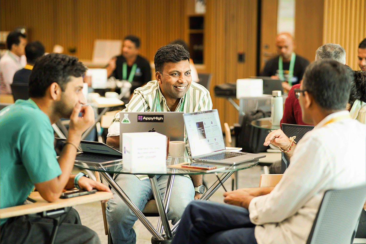 A speaker addresses two engaged listeners with a laptop in front of them.