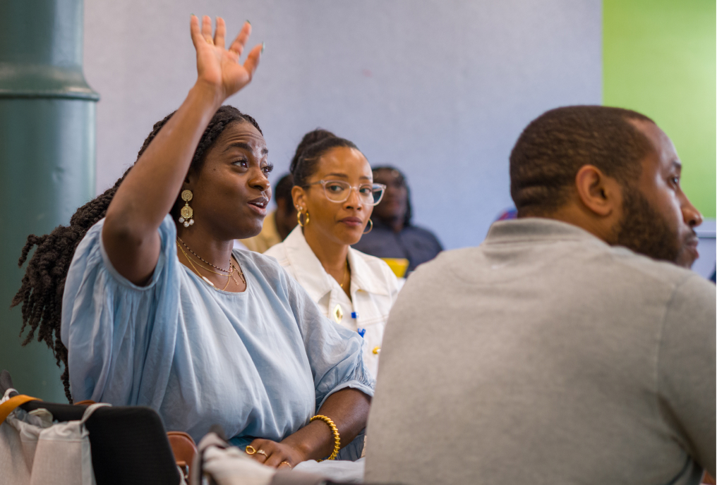 A woman raised her hand to ask a question, drawing the attention of those around her.