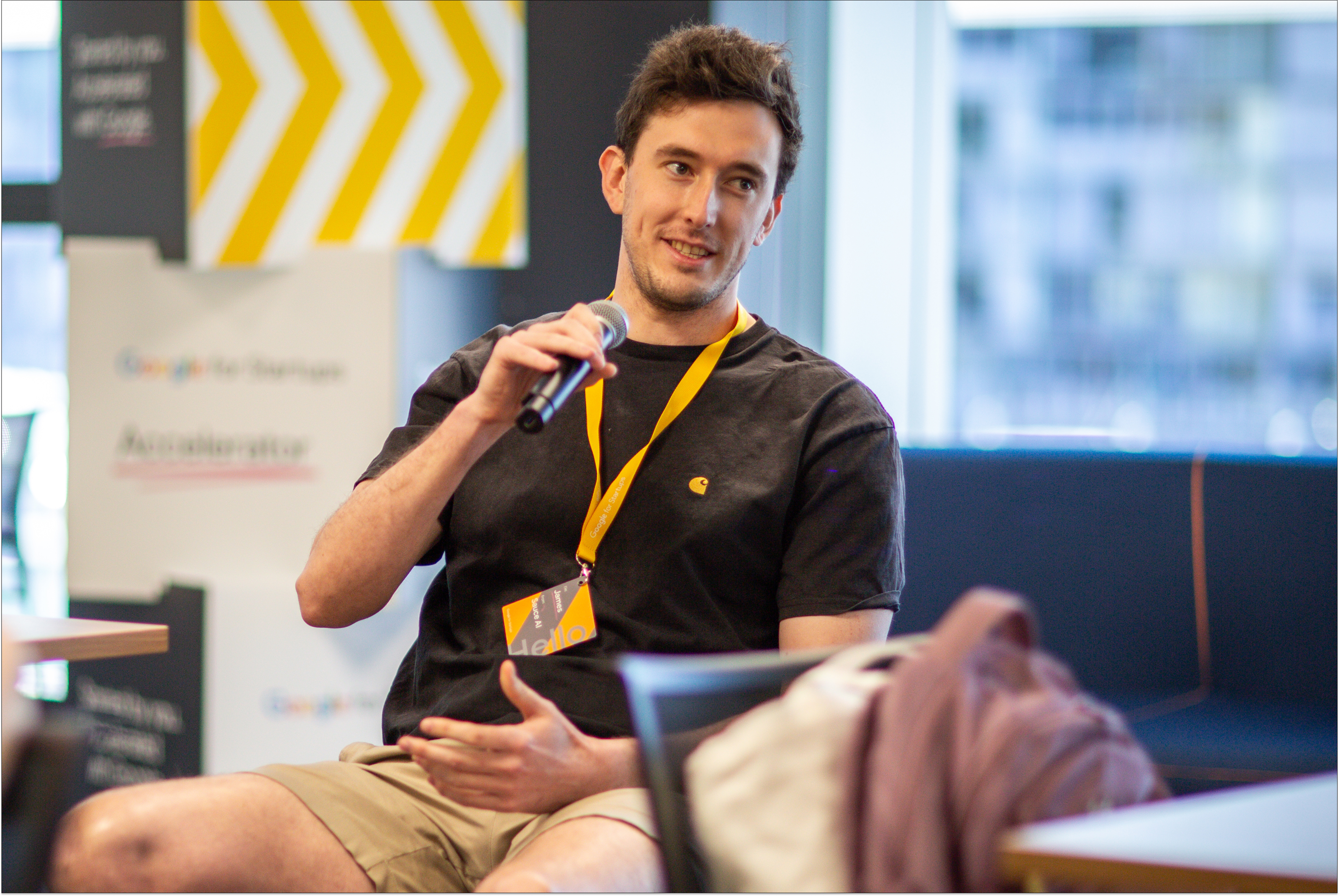 A person is seated on a stage, engaged in a discussion.
