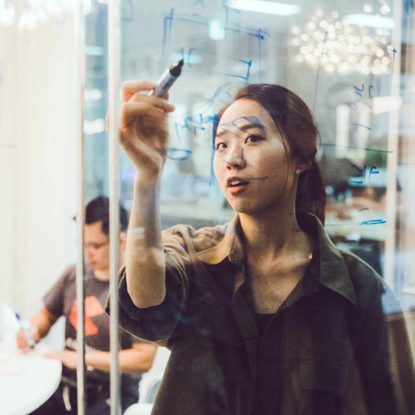 Woman writing on glass board