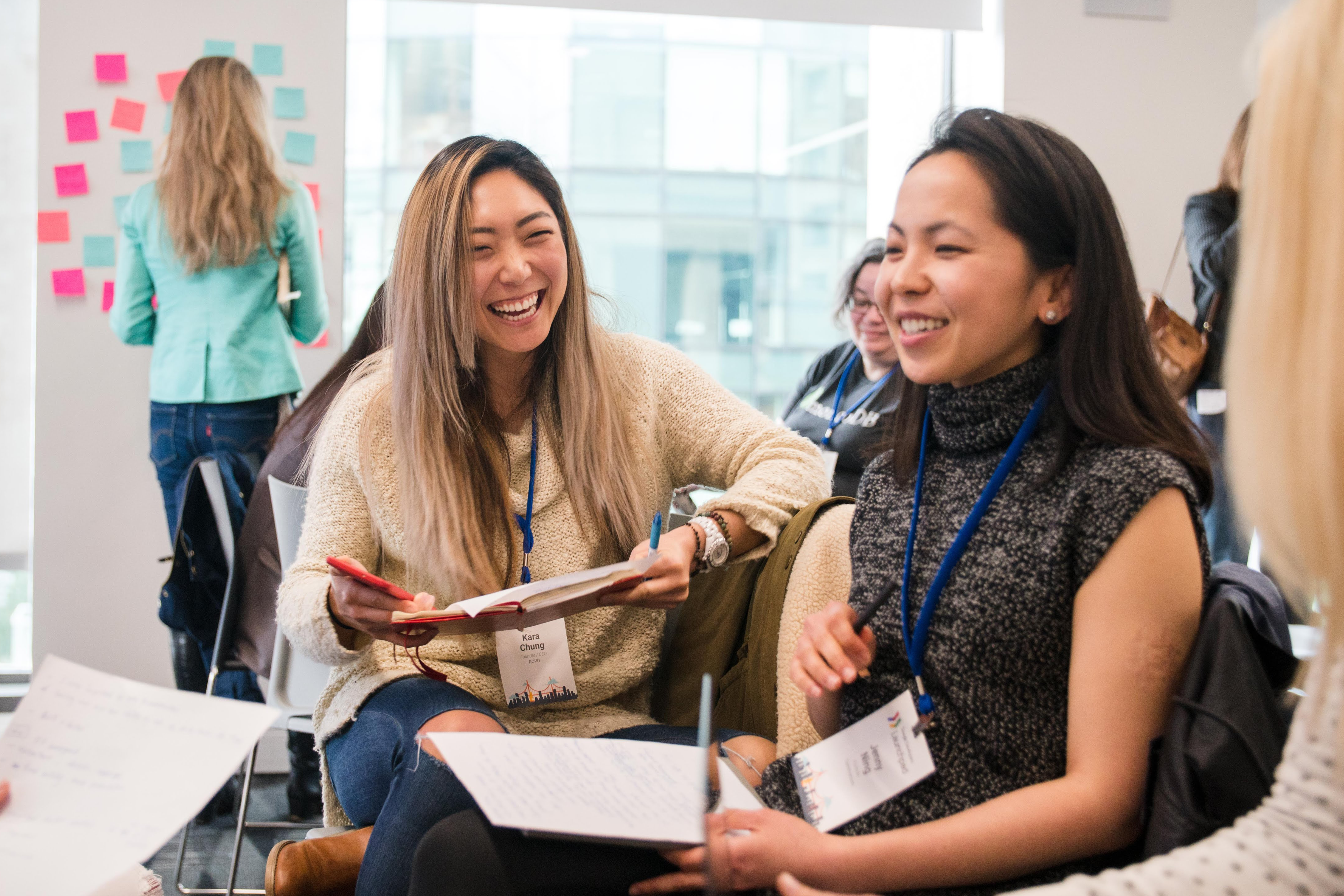 The two seated women in the group are conversing happily.