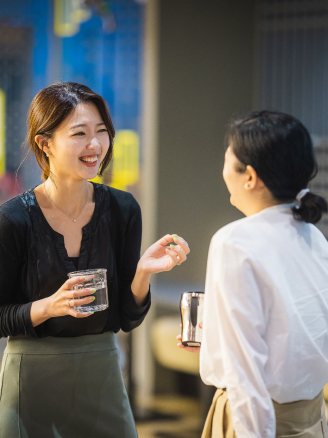 Two women standing with cups, laughing