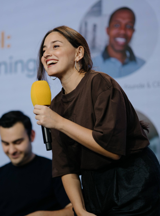 A young lady giving a speech on the microphone with a smiling face.