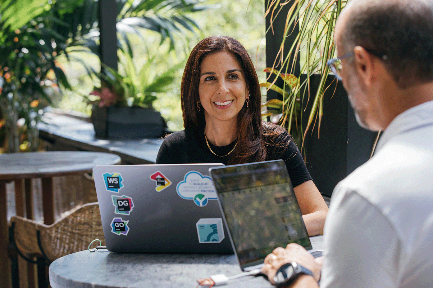 A man and woman discussing something over their laptops.