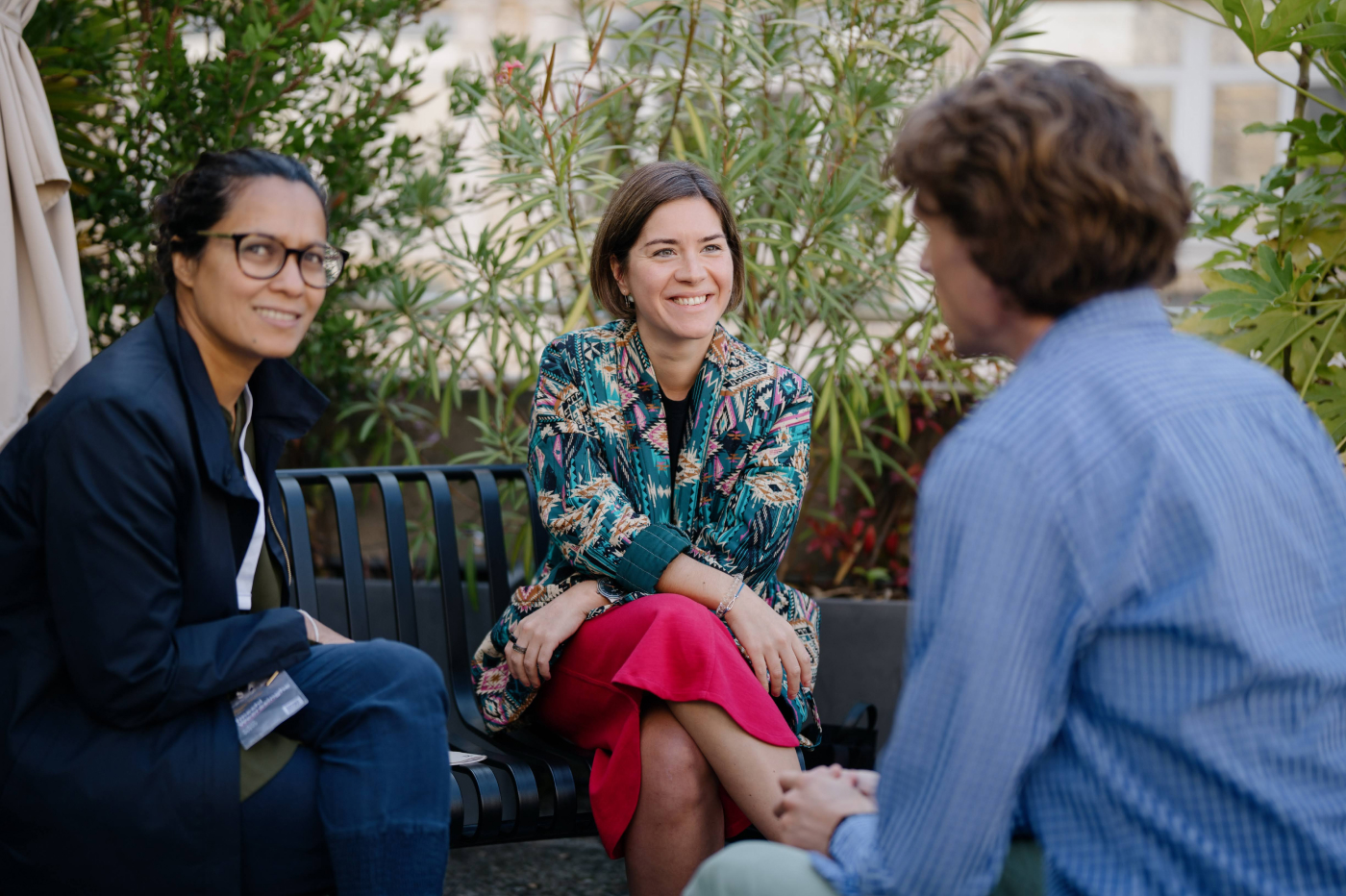 Two women and a man are having a friendly conversation with smiles on their faces.