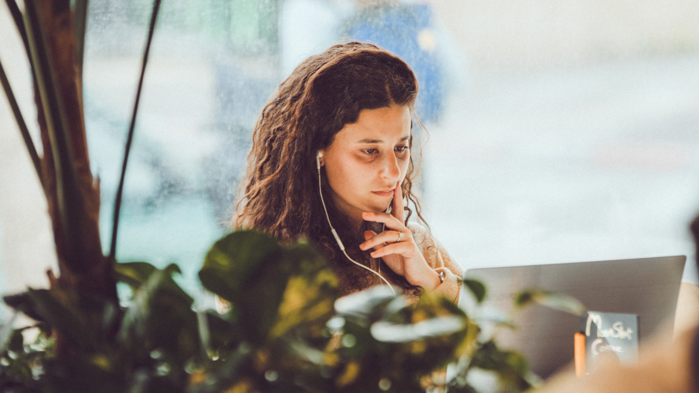 A woman looking into a laptop and watching something.