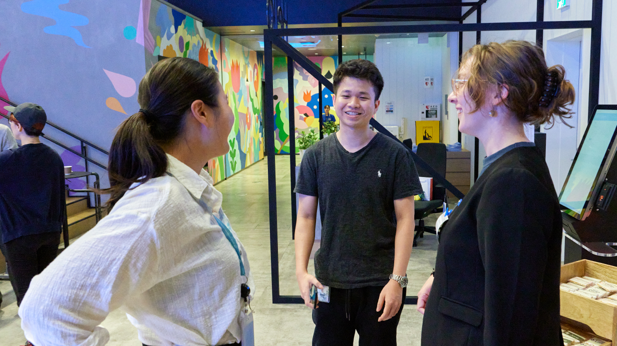 2 girls and a boy discussing something while standing in a circle