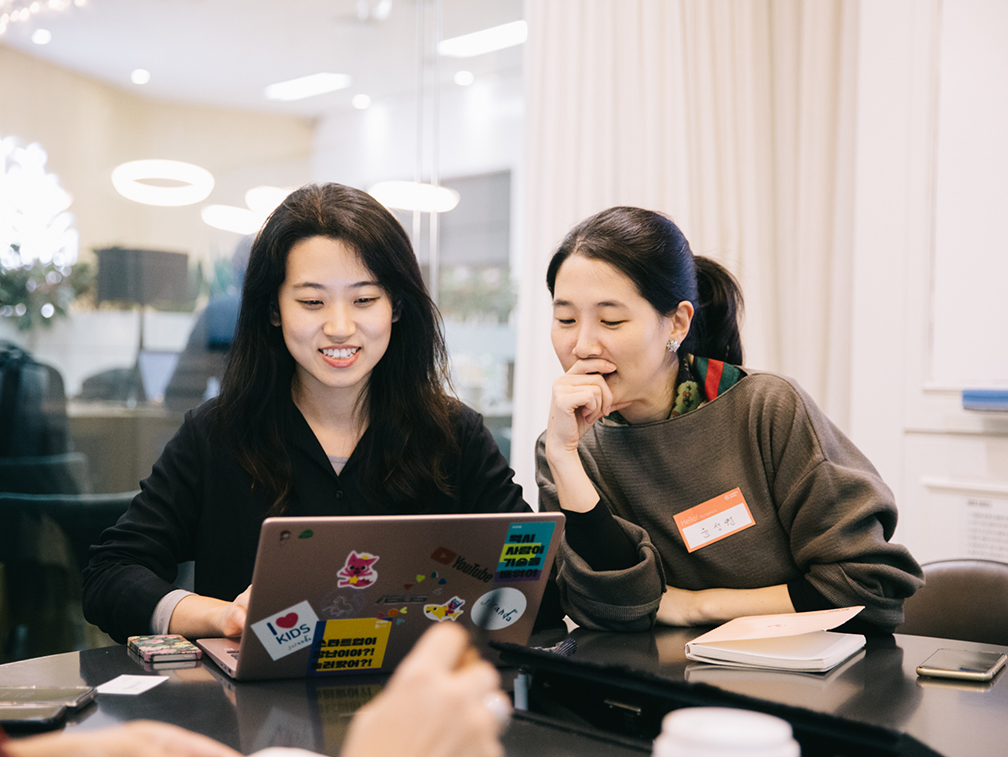 Two ladies are working on a laptop.