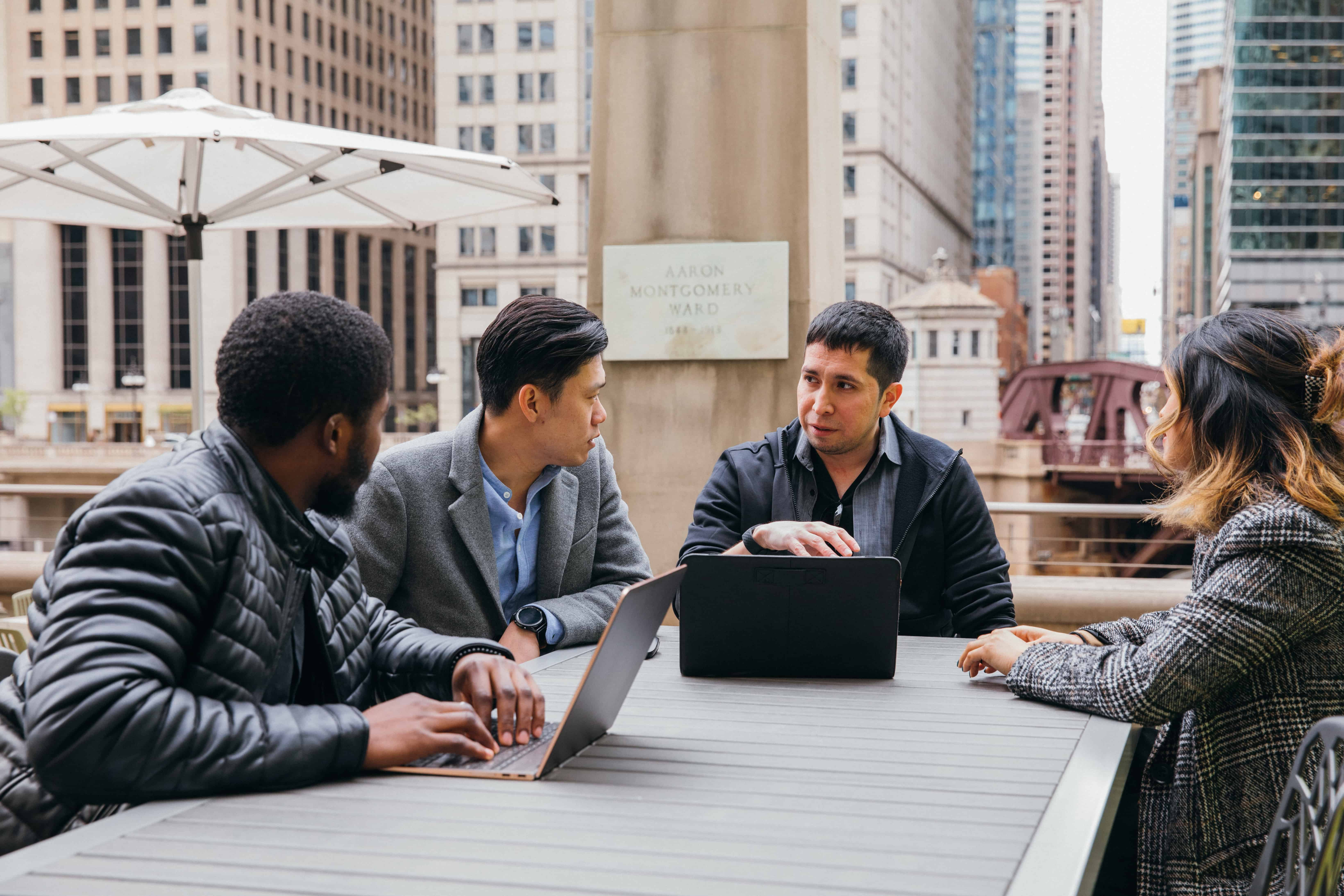 3 men and a woman sitting around a table, discussing.