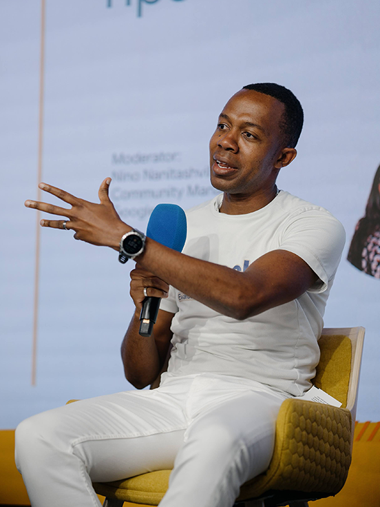 One person on stage, holding microphones and speaking at the event.