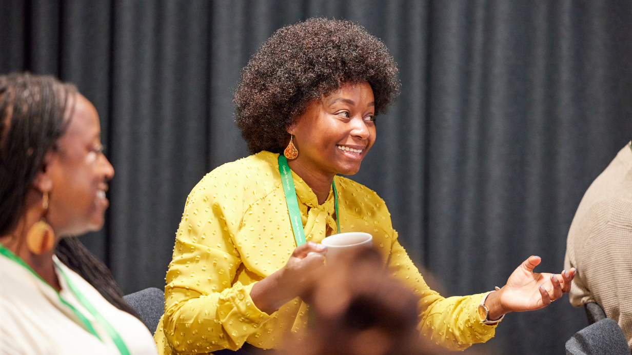 A woman holding coffee cup while smiling and discussing something