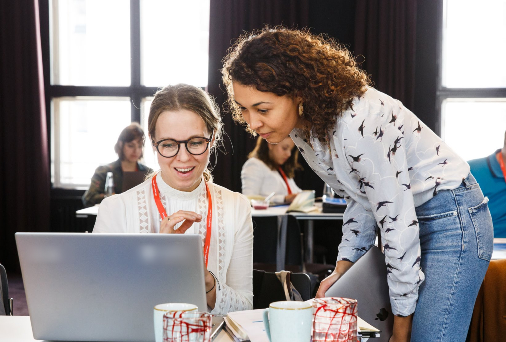 Two women looking into the laptop screen and discussing something.