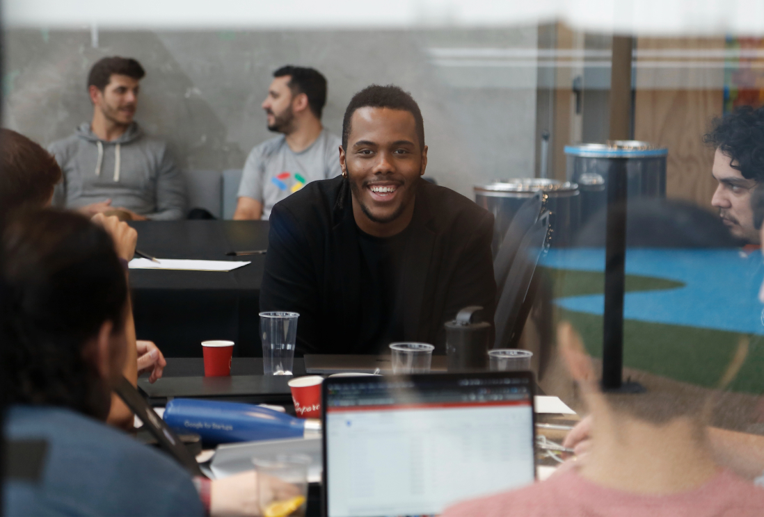 A man sits around a table looking at the camera and smiling.