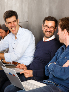 Três homens sorrindo e discutindo ideias