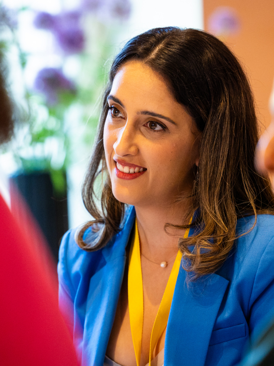 A woman in a blue suit listens with a smile.