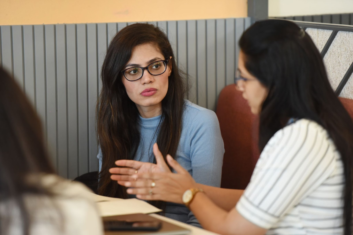 Two women are sitting on a chair and discussing something