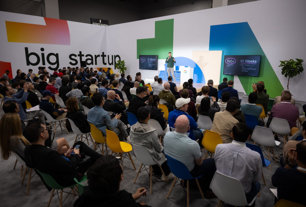 A presenter wearing a green shirt is delivering a presentation on a startup.