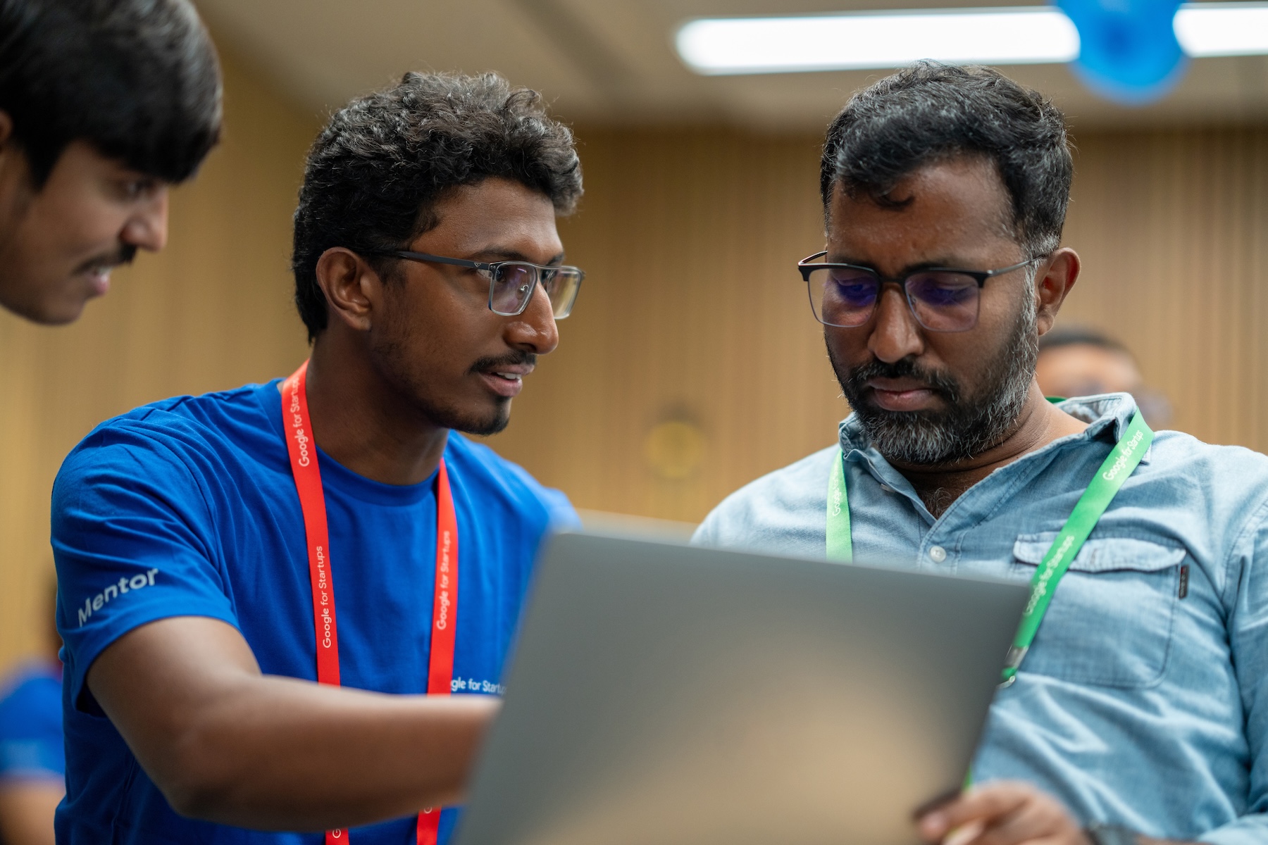 A man wearing red lanyard explaining something to other man who wore green lanyard .