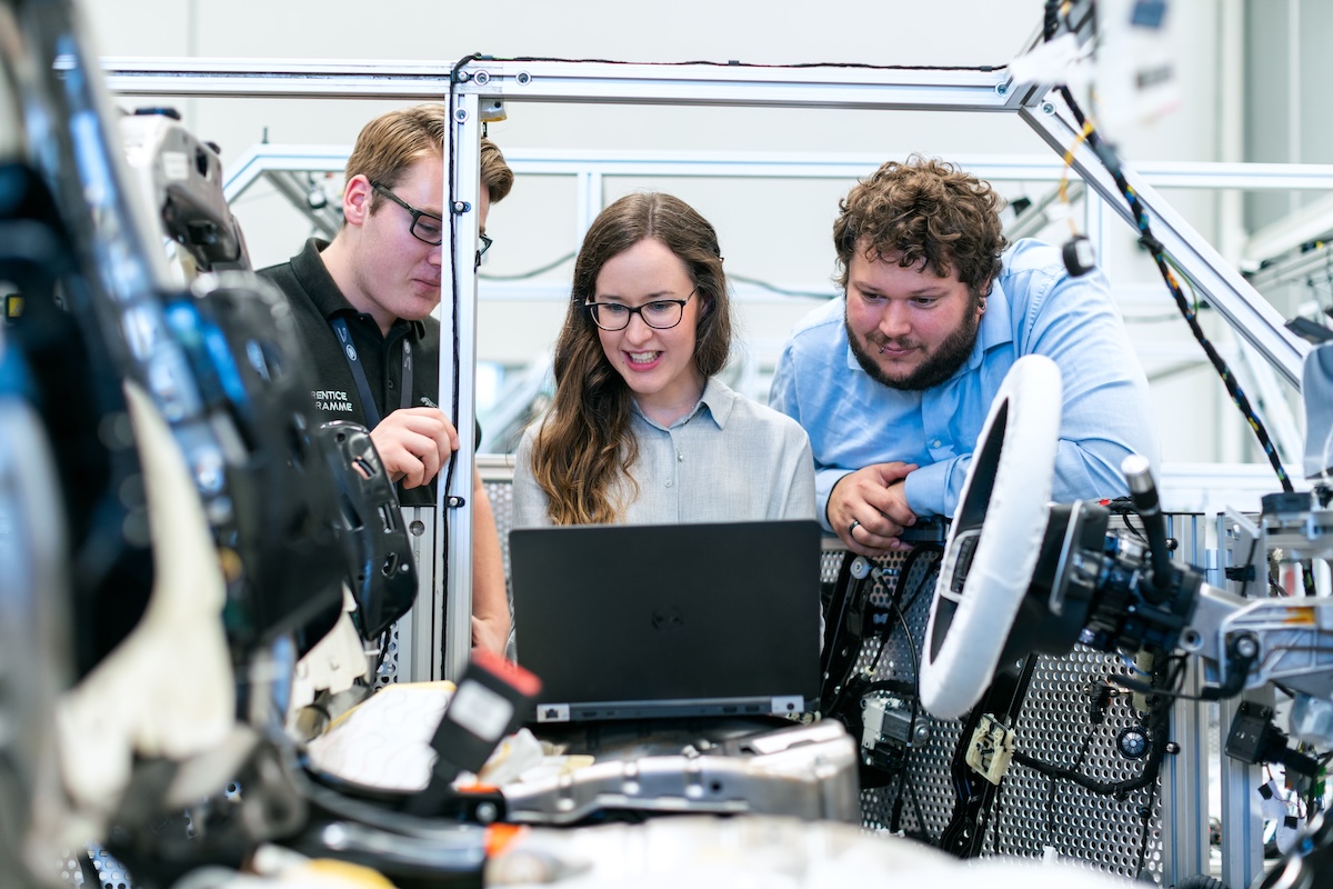 Two men and a woman looking something on a laptop