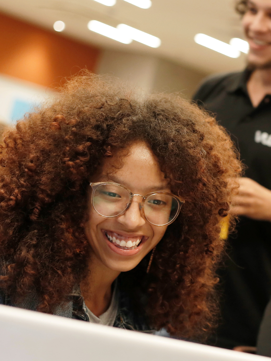 A girl is smiling looking at the screen.