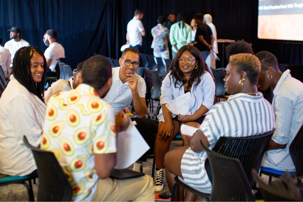 A team seated on a chair facing away from the camera, discussing.