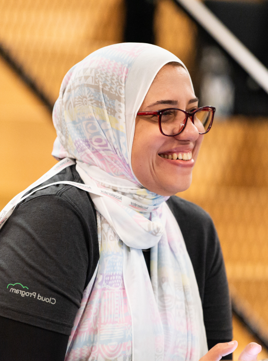 A woman wearing a scarf and a spectacles is smiling.