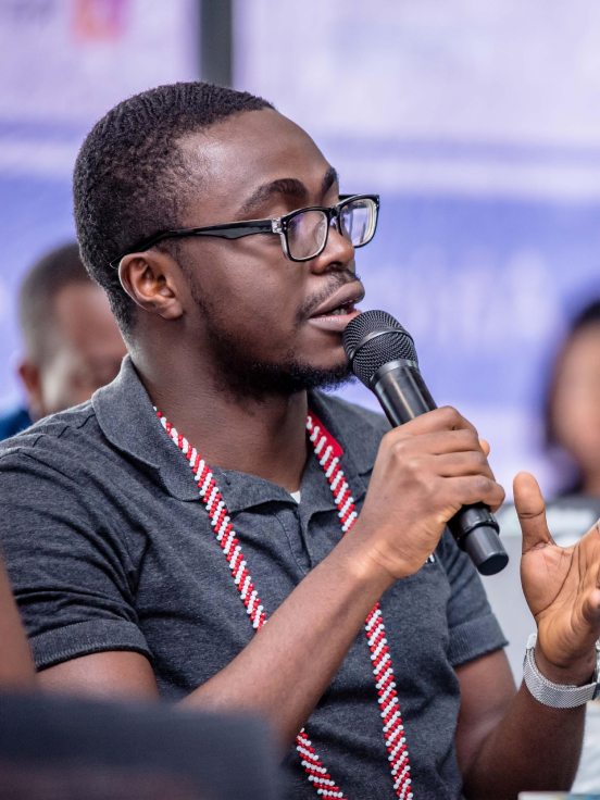 A men is speaking something in mic while his laptop is open in front of him