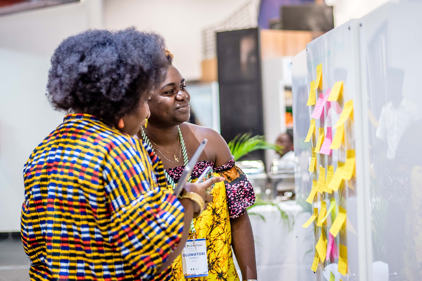Two women examine a sticky note board at the event.