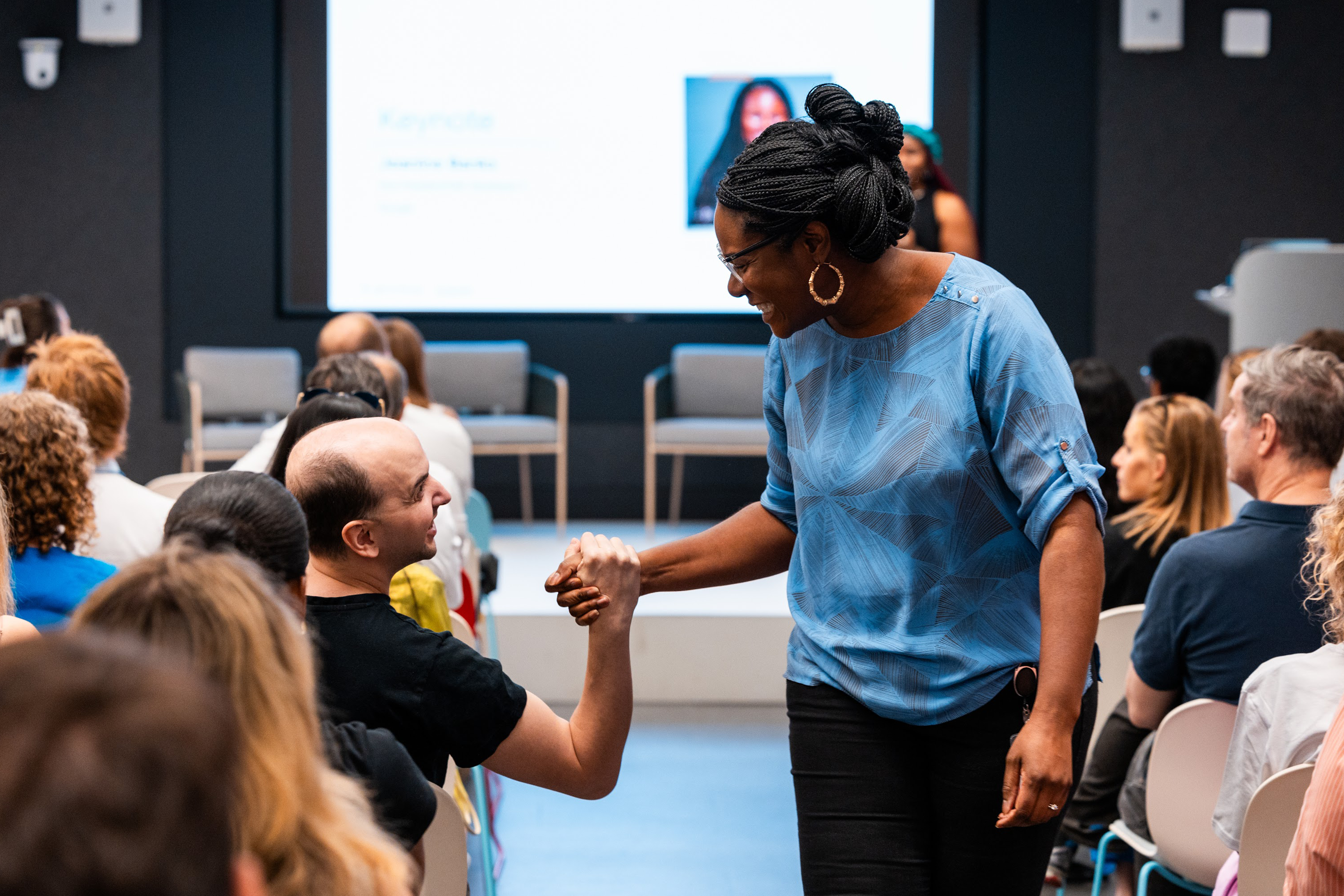 The female host shakes the hand of an audience member.