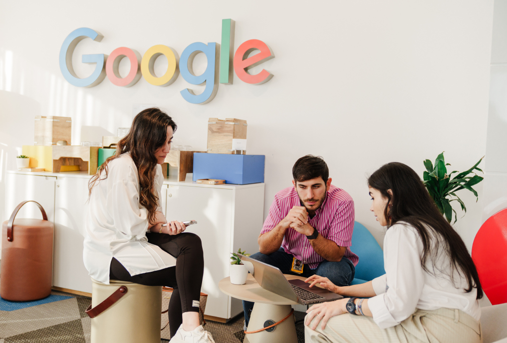 3 people sitting around a table and working.