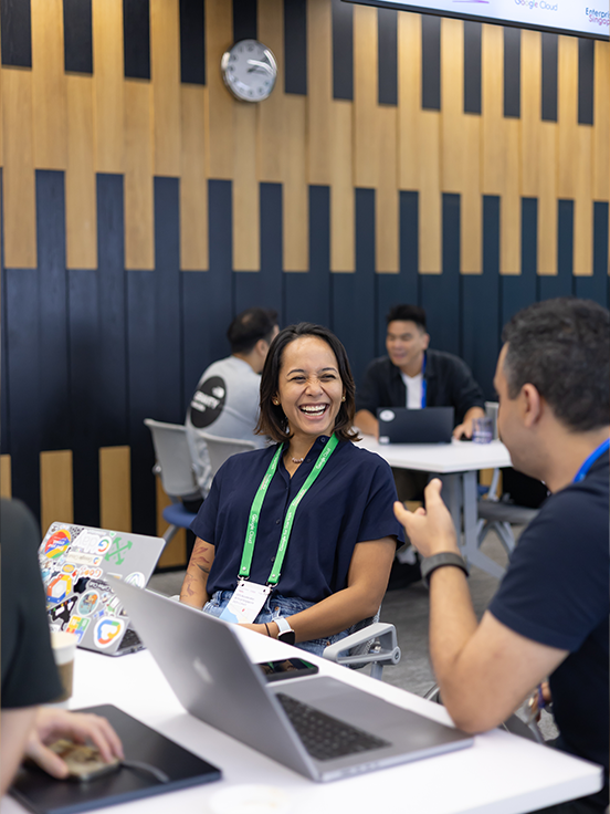 Men and women having a discussion at an event table with a laptop.