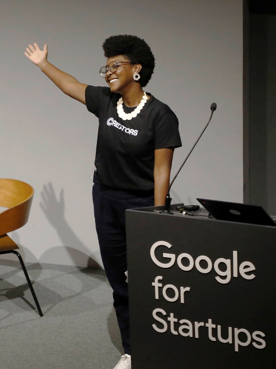 A women wearing a black t-shirt showing something by directing a hand.