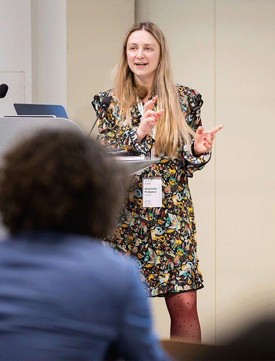 A smiling lady is hosting the event and presenting something.